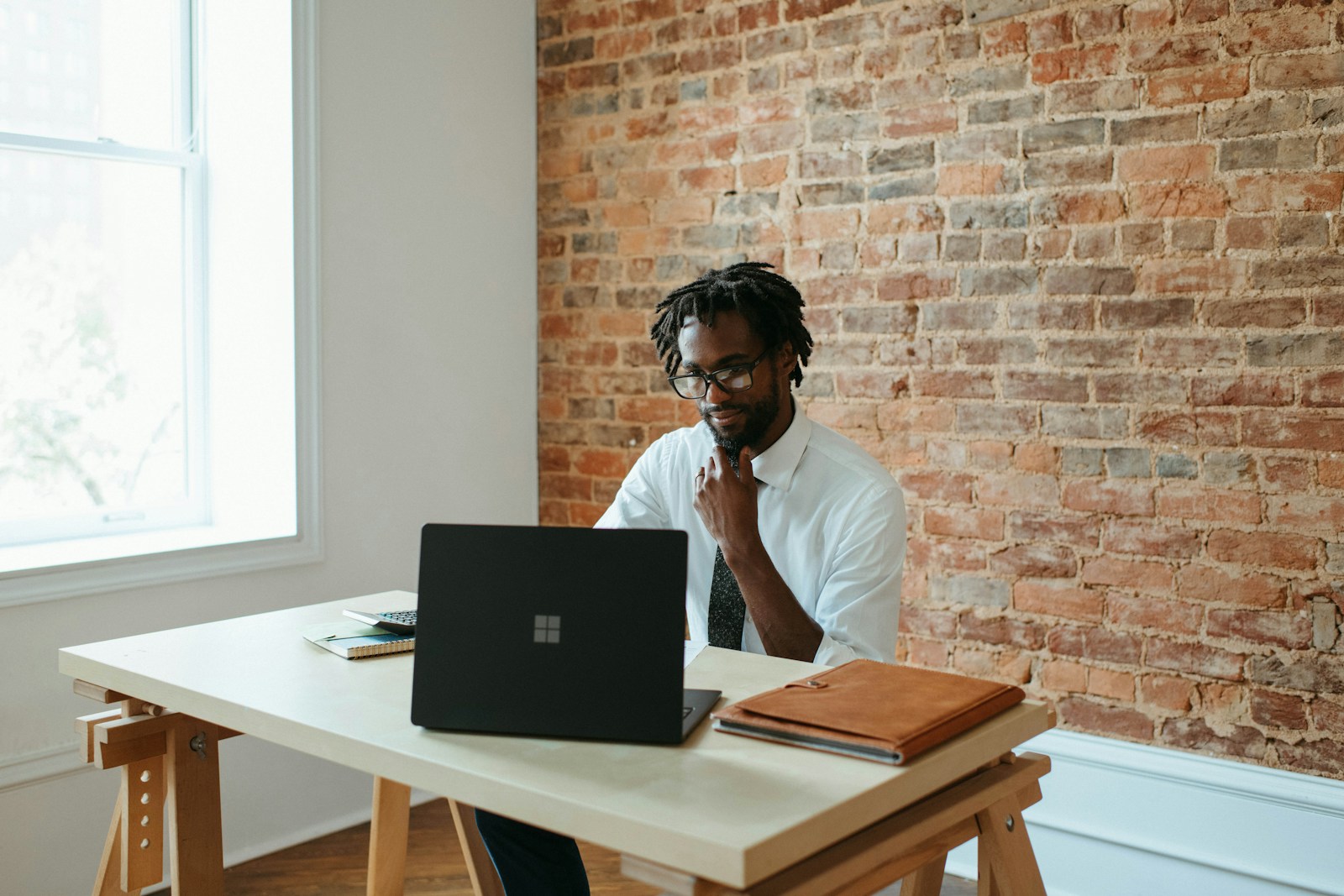 a man sitting at a table in front of a laptop focusing on his business